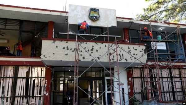 FILE - Workers repair the entrance of City Hall riddled with bullet holes in Villa Union, Mexico, Dec. 2, 2019, after 22 people were killed in a weekend gun battle between a drug cartel and security forces.